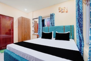 A bedroom with a bed, a wardrobe, a window with curtains, and a wall with artwork. - Hotel O AIIMS Bhubaneswar Road (Bhubaneshwar)