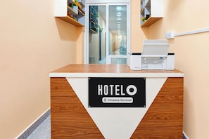 A reception desk with a sign reading 'HOTELO Company Serviced' and a printer on top.