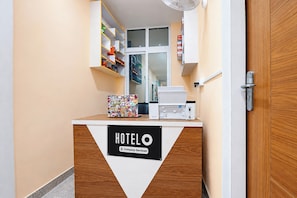 A hotel reception desk with a sign indicating company-serviced rooms, a fan, and a window with a view. - Hotel O AIIMS Bhubaneswar Road (Bhubaneshwar)