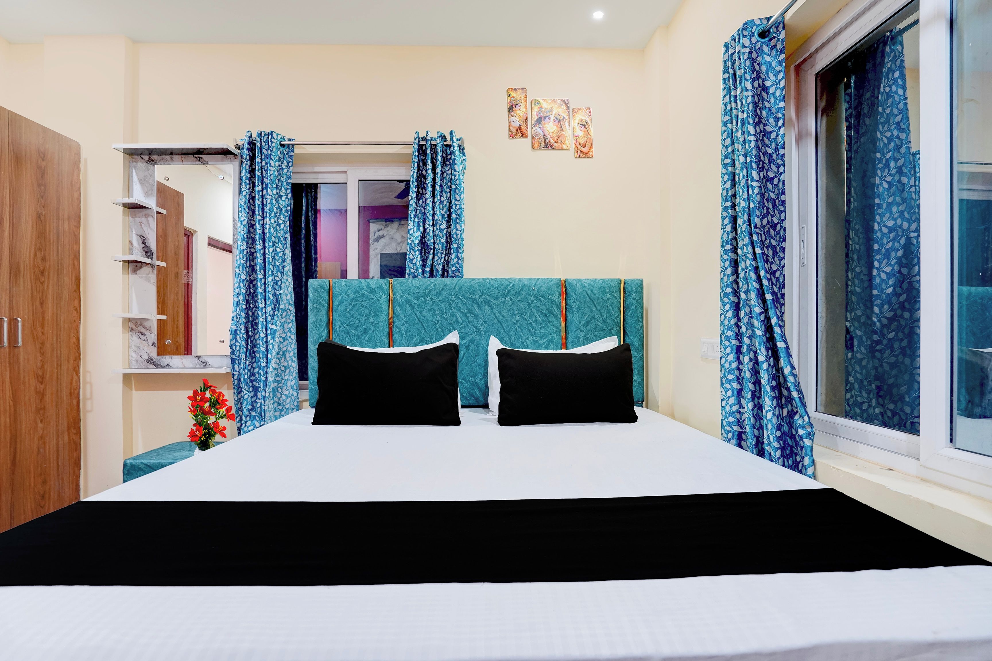 A bedroom with a bed, curtains, a wardrobe, and a window.