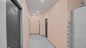 Un pasillo con puertas a ambos lados, suelo de baldosas e iluminación empotrada en el techo.