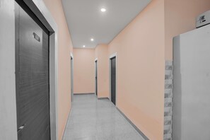 Ein Korridor mit Türen an beiden Seiten, einem Kachelboden und einer Decke mit eingelassener Beleuchtung.