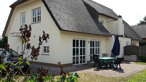 A house with a large patio, a dining table, and chairs.