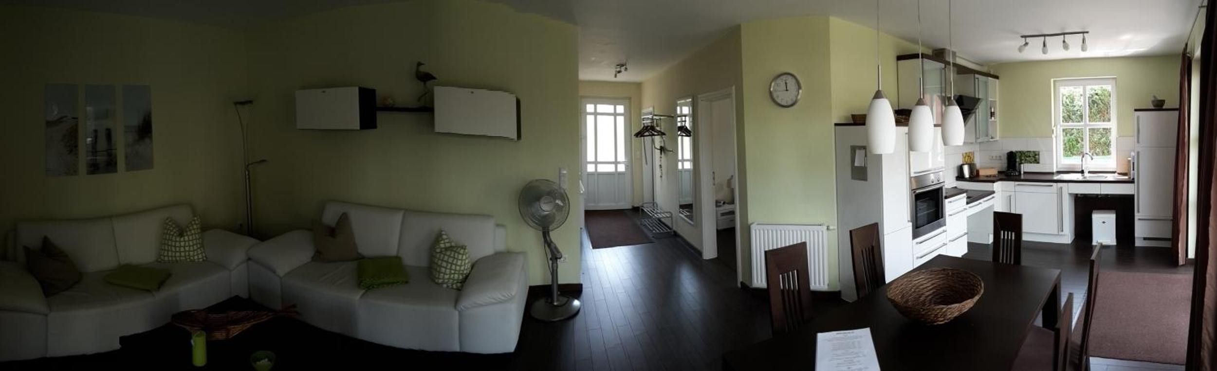 Ein Wohnzimmer mit einer Couch, einem Ventilator und einem Essbereich mit Tisch und Stühlen.