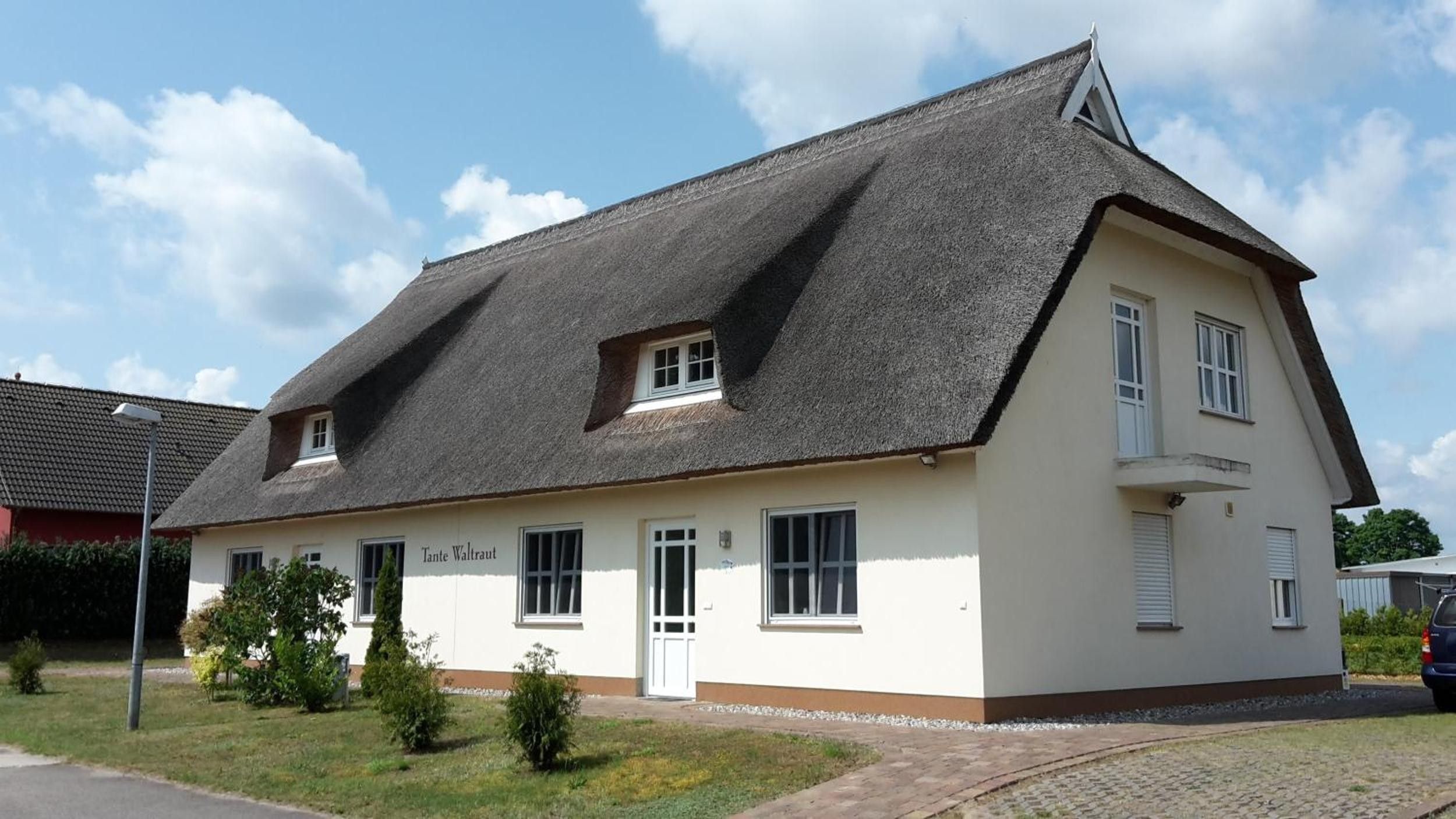 A two-story building with a steeply pitched roof, a small dormer window, and a white facade.