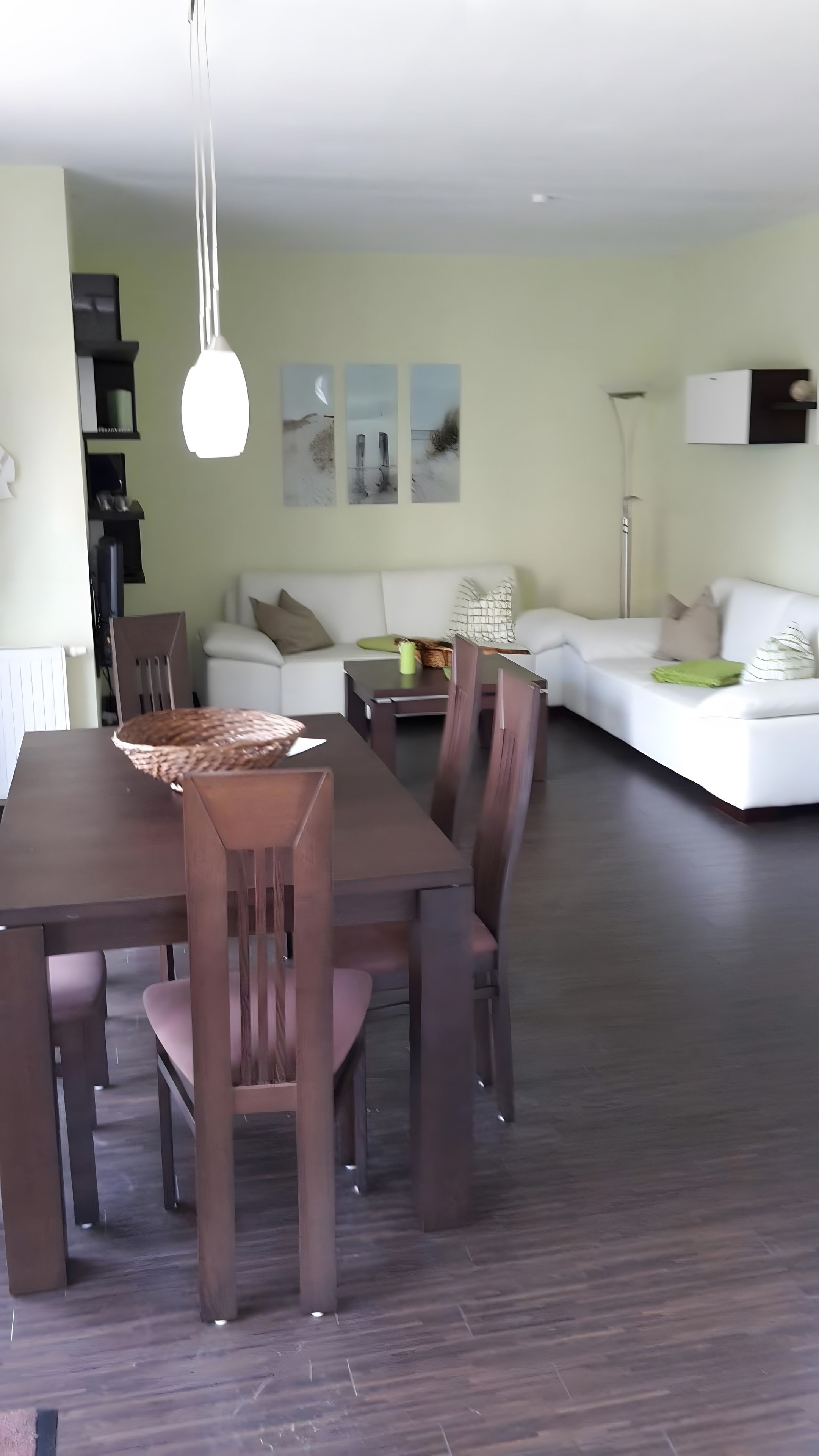 Un comedor con una mesa y sillas de madera, un sofá blanco y una lámpara de pie.