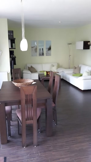 A dining area with a wooden table and chairs, a white sofa, and a floor lamp.