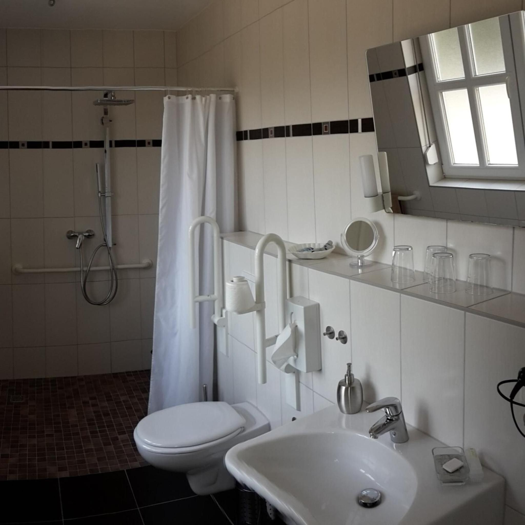 A modern bathroom with a toilet, sink, shower, and a window.