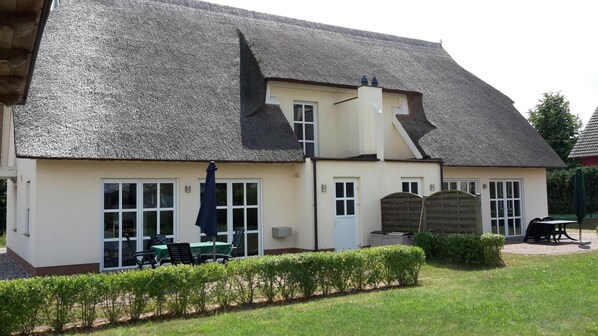 A building with a thatched roof, large windows, and a patio area with outdoor seating.