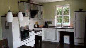 Une cuisine moderne avec des meubles blancs, un four encastré, un évier et une fenêtre qui laisse entrer la lumière naturelle.