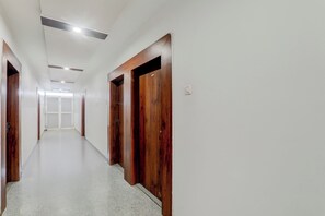 A corridor with wooden doors and white walls, leading to a bright room at the end. - Collection O Bihar Sharif (Bihar Sharif)