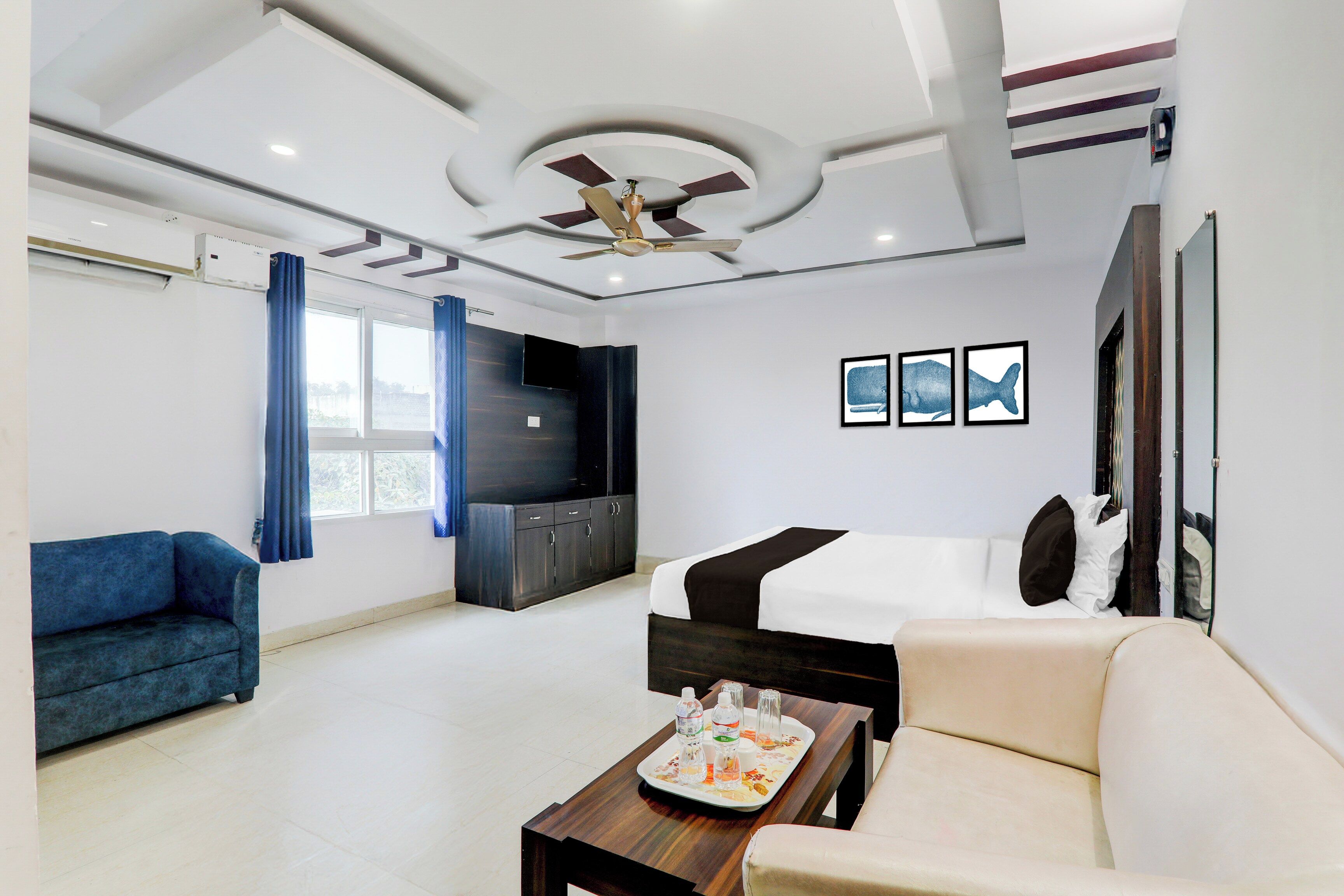 Una habitación de hotel con cama, sofá, televisor y ventilador de techo.