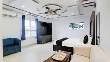 Una habitación de hotel con cama, sofá, televisor y ventilador de techo.