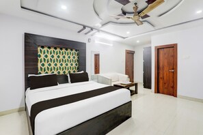 Een moderne slaapkamer met een groot bed, een plafondventilator en een behang met patroon.
