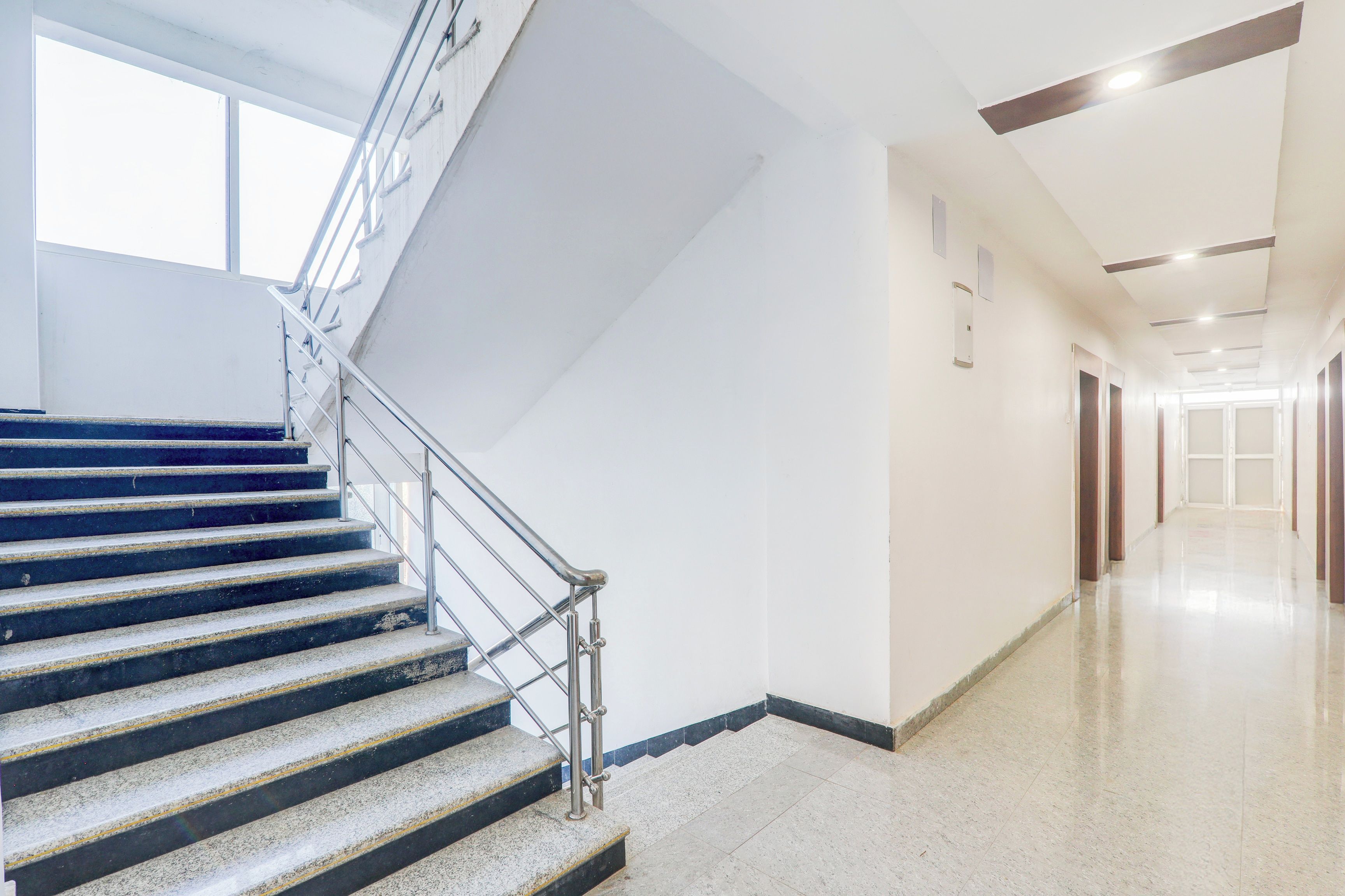 A modern interior with a staircase, a hallway, and a door at the end.