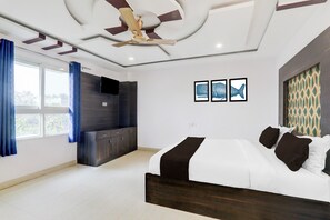 Een moderne slaapkamer met een bed, een televisie en een plafondventilator.