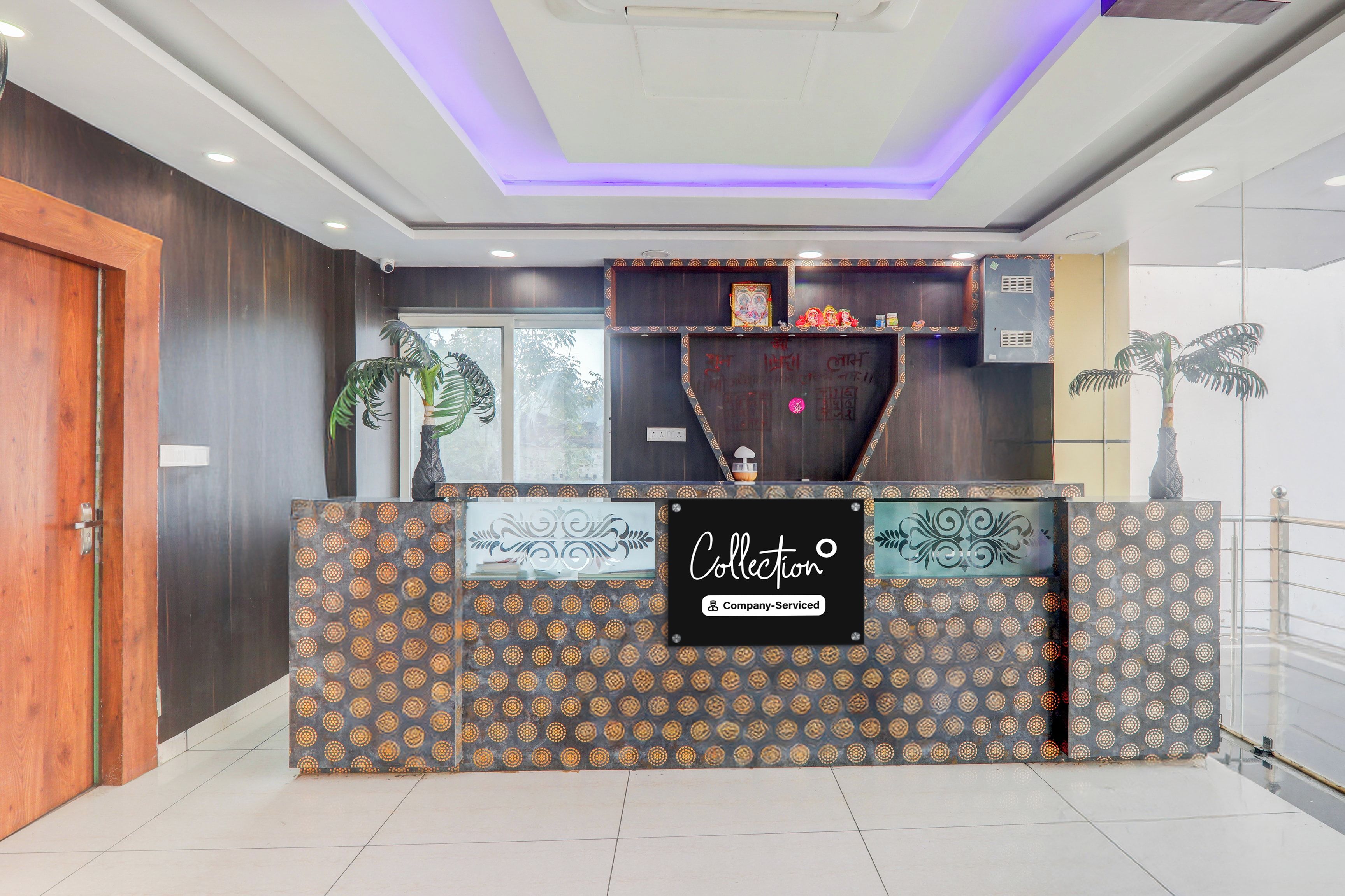 Un mostrador de recepción con un diseño estampado, un cartel que indica servicios de la empresa y una estantería decorativa arriba.