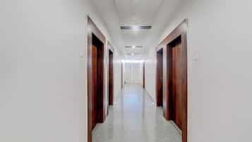 A long, narrow hallway with wooden doors on both sides and a tiled floor.
