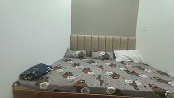 A single bed with a headboard, a pillow, and a blanket with a floral pattern.