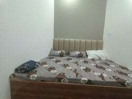 Una cama individual con cabecera, almohada y colcha estampada con motivos florales.