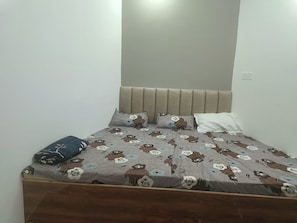 A single bed with a headboard, a pillow, and a blanket with a floral pattern.