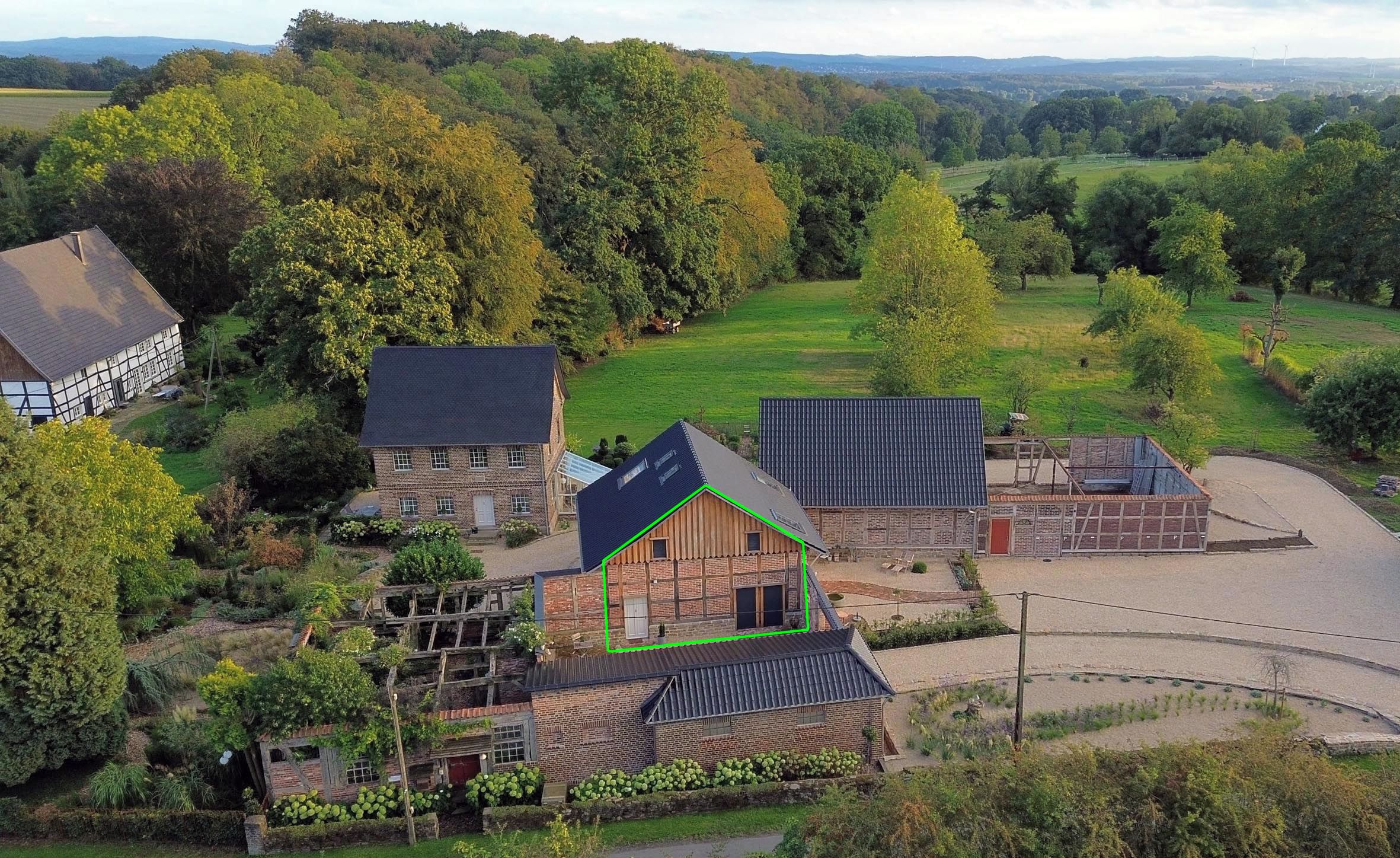 Il s’agit d’une propriété rurale comprenant plusieurs bâtiments, notamment une maison avec un toit en pente, une grange et un espace clôturé équipé de panneaux solaires.