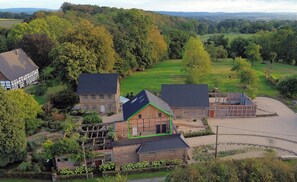 A rural property with multiple buildings, including a house with a sloped roof, a barn, and a fenced area with solar panels.