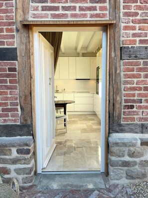 A doorway leading into a modern kitchen with white cabinets and a tiled floor.