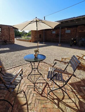 An outdoor seating area with a table and chairs, a large umbrella, and a brick building in the background. - Small country house surrounded by greenery, peace and quiet, nature, a break from it all, breakfast included (Fröndenberg/Ruhr)
