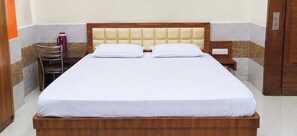 Een opgemaakt bed met een houten hoofdbord en een nachtkastje met een lamp.