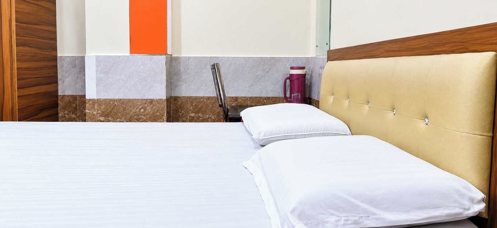 A hotel room with a bed, a wooden headboard, a nightstand, and a red coffee maker.