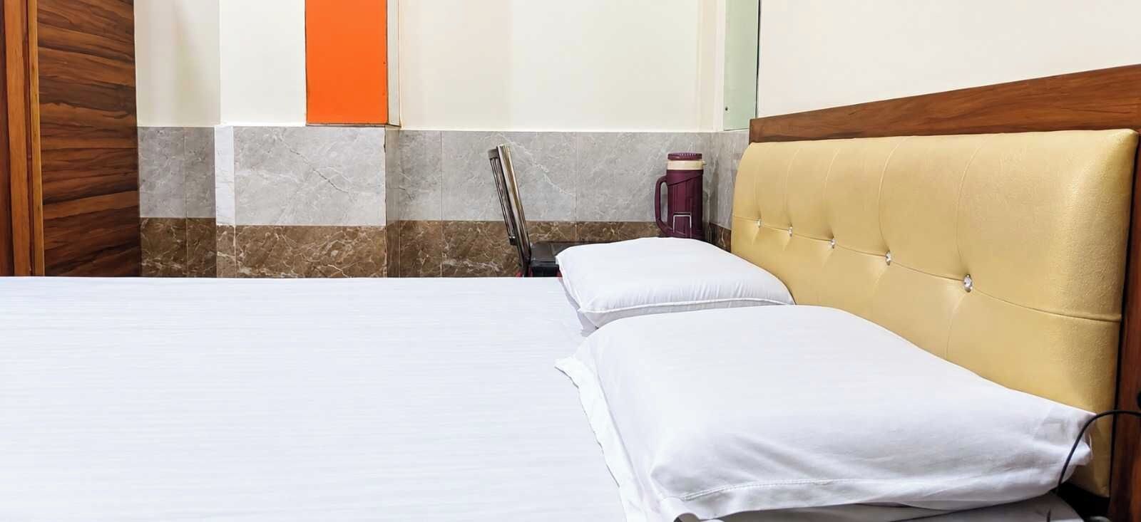 A hotel room with a bed, a wooden headboard, a marble wall, and a red accent wall.