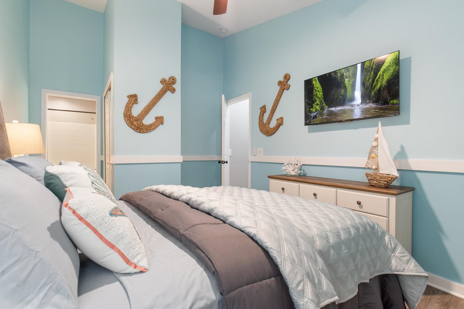 A bedroom with a bed, a television, and decorative wall anchors.