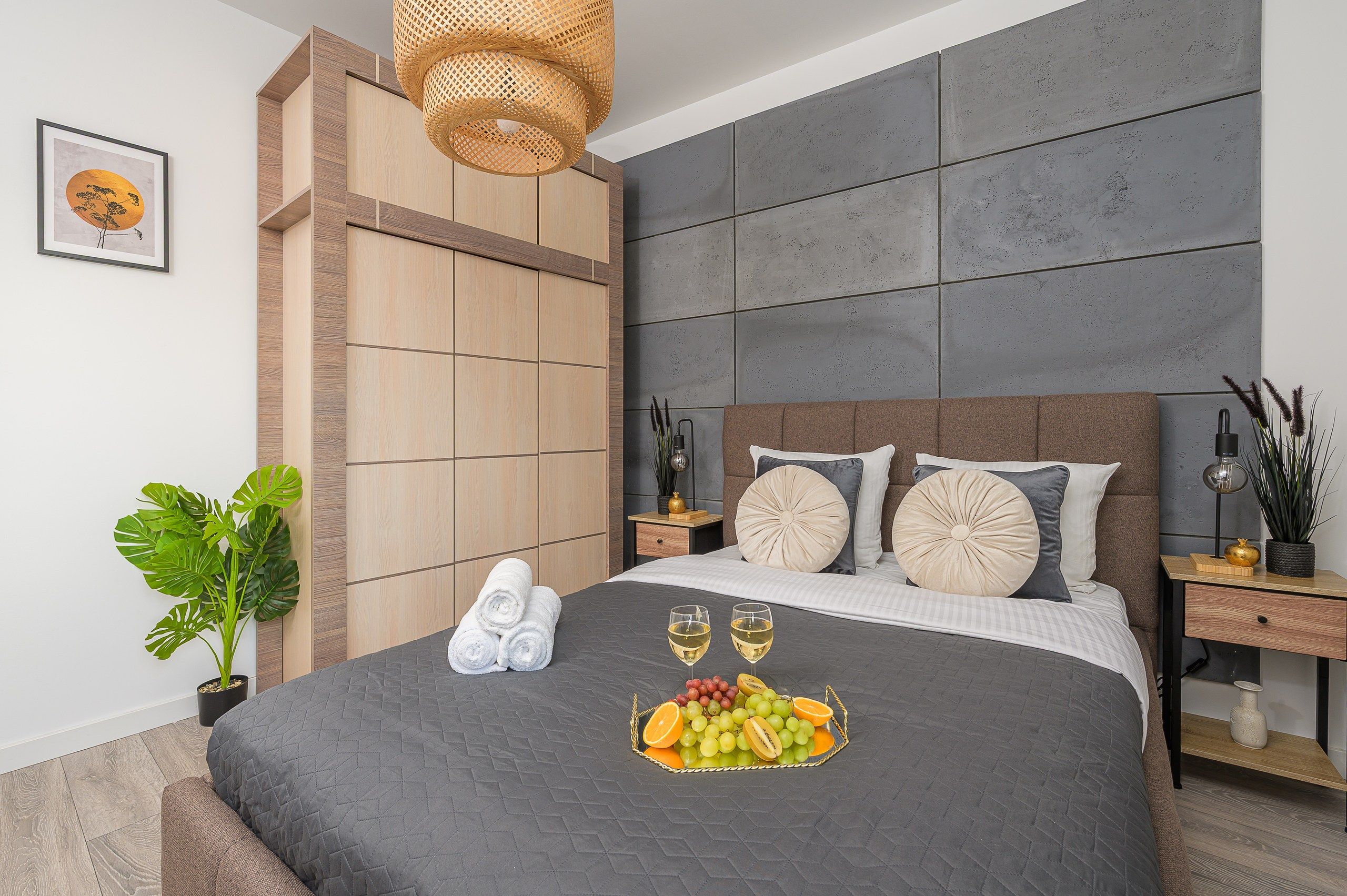 Un dormitorio moderno con una cama grande, una mesita de noche, una lámpara colgante y un cuadro en la pared.