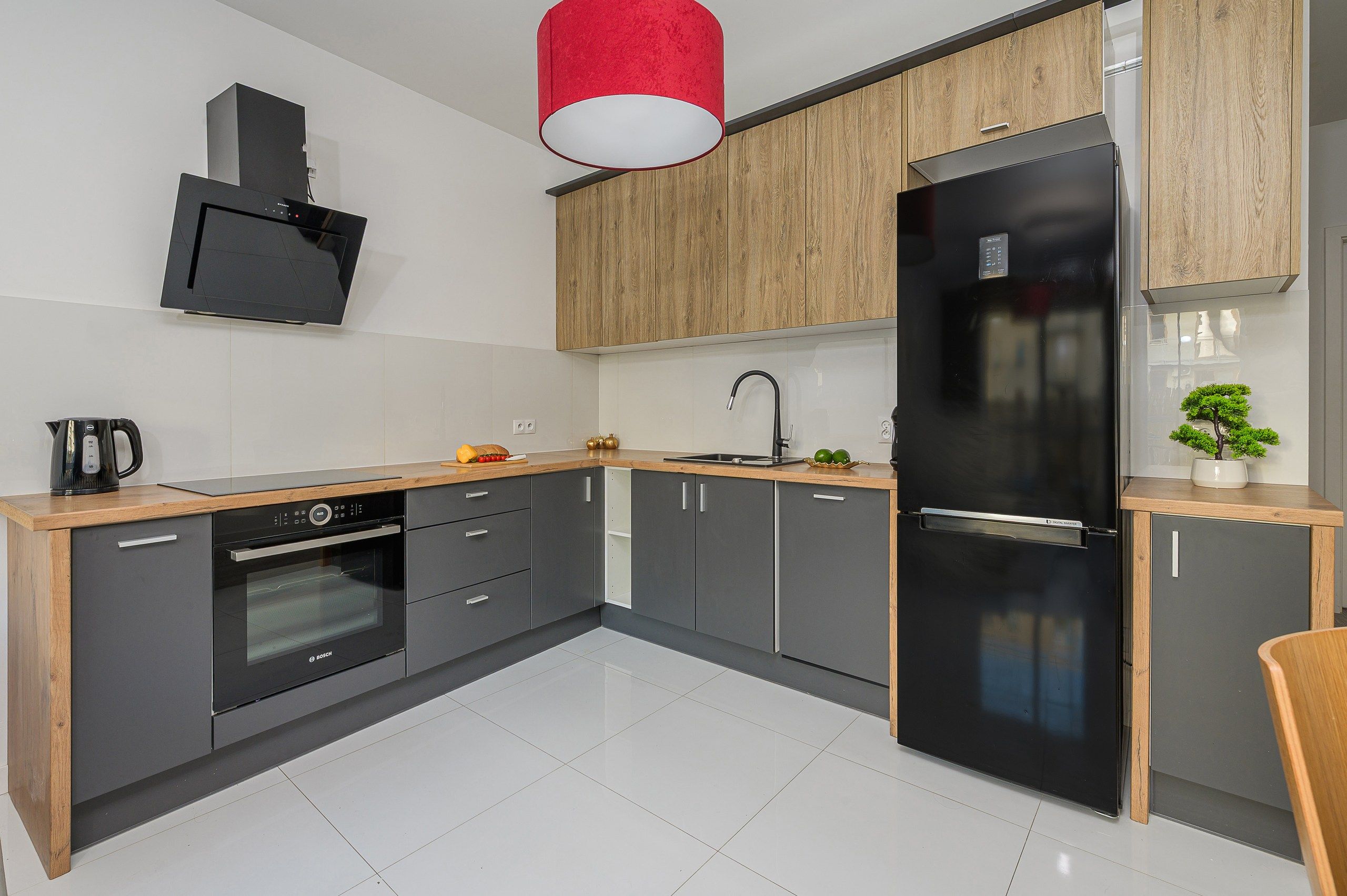 A modern kitchen with a Bosch oven, a black refrigerator, and wooden cabinets.