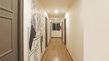 Un pasillo con suelo de madera, paredes blancas y puertas con contorno negro.