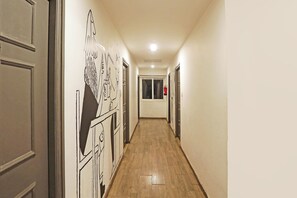 Un pasillo con suelo de madera, paredes blancas y puertas con contorno negro.
