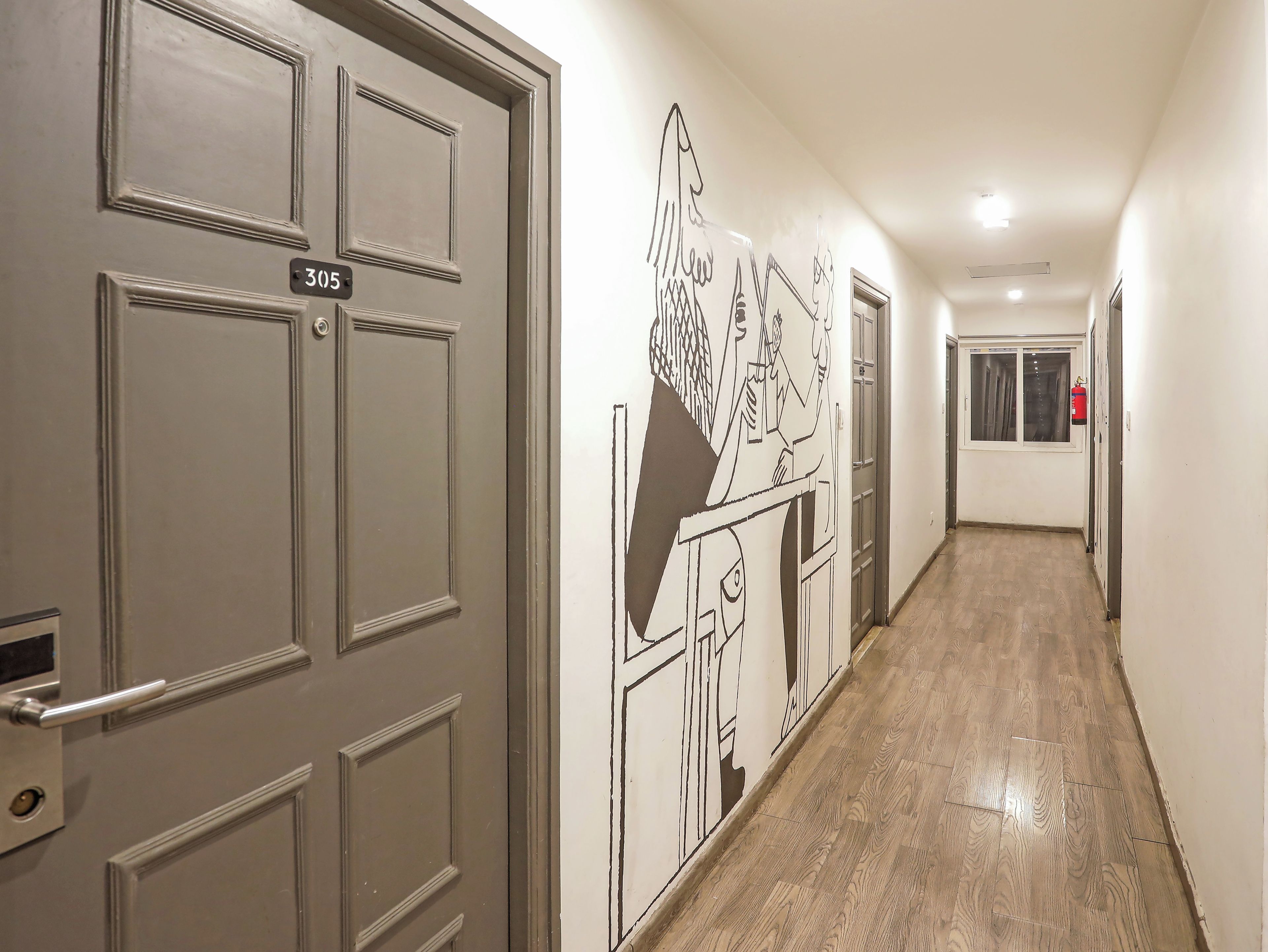 Un pasillo con una puerta que tiene el número 305 y un mural en la pared.