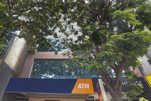 An ATM sign on a building facade with a tree in the foreground. - Townhouse 600 - Secunderabad near  (Hyderabad)