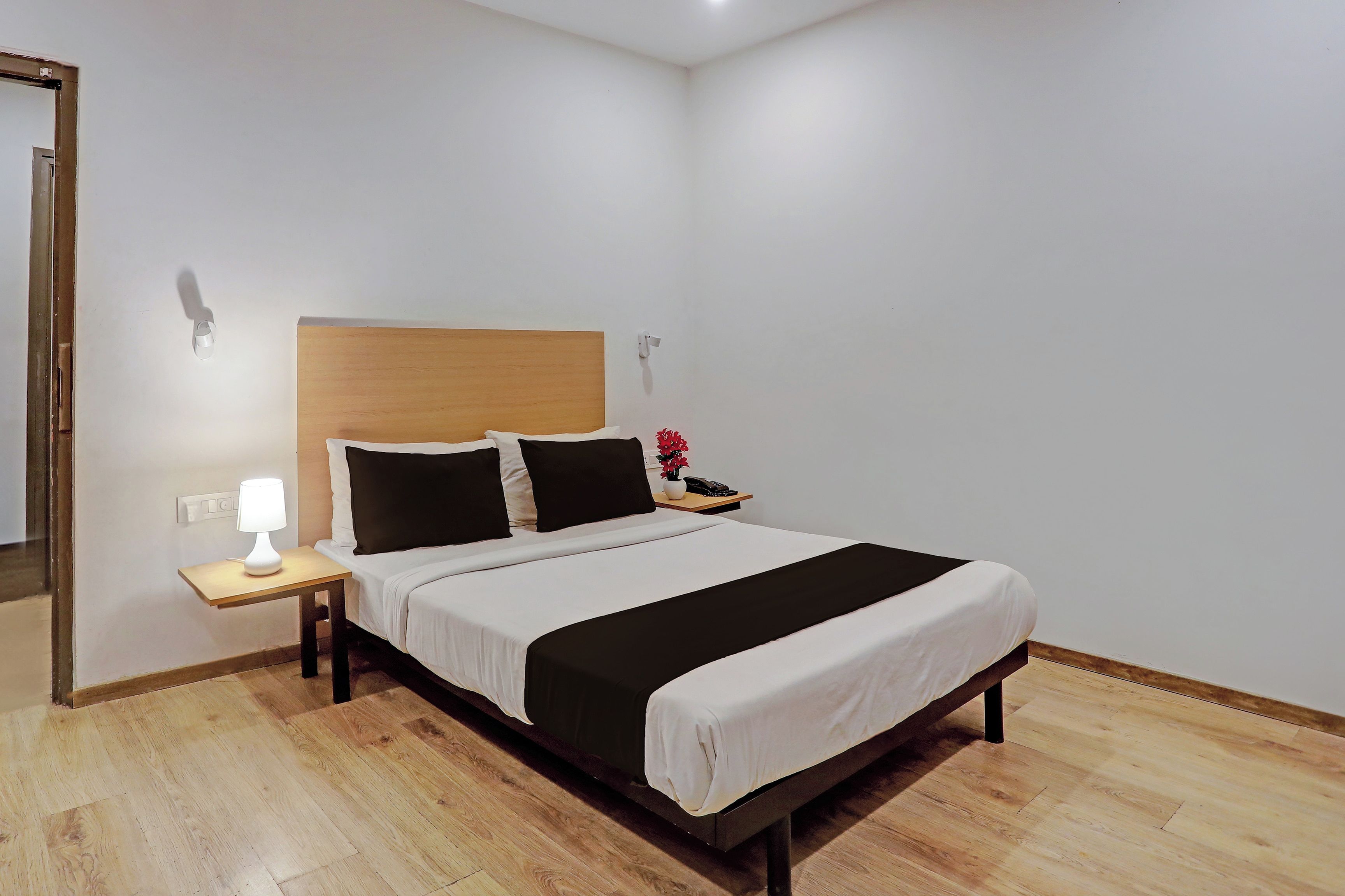 Une chambre d’hôtel avec un lit, une table de chevet, une lampe et une petite plante en pot.