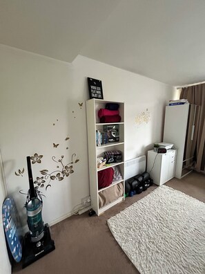 A room with a white bookshelf, a vacuum cleaner, a white rug, and a clock on a cabinet. - Central London Studio Apartment- walking distance from the London Eye/Big Ben (London)