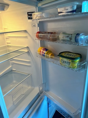 Un refrigerador abierto con dispensador de agua, una mantequilla Lurpak y un recipiente con suero de leche Clover Simply.