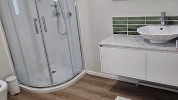A modern bathroom with a glass-enclosed shower, a white sink, and a mirror above it.