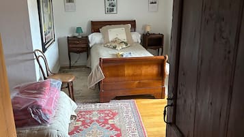 Un dormitorio con una cama de madera, una mesita de noche con lámpara, una silla y una alfombra.