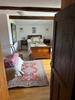Une chambre à coucher avec un lit en bois, une table de chevet avec une lampe, une chaise et un tapis.