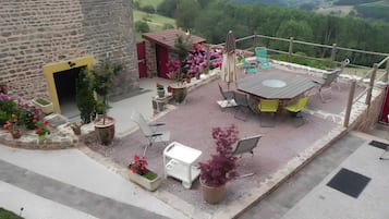 Un patio al aire libre con una mesa y sillas, rodeado de macetas con plantas y flores.