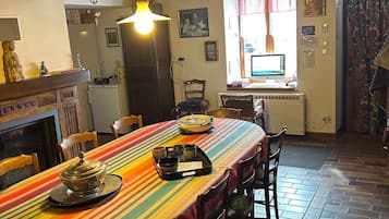 Un comedor con una mesa larga, sillas, una chimenea y una ventana con cortinas.