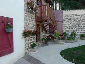 A stone building with a wooden staircase and red shutters.