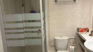 Een badkamer met een douchecabine, toilet en wastafel.