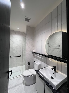 Un baño moderno con inodoro, lavamanos y ducha.